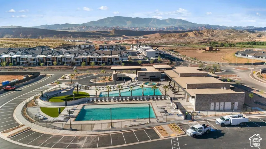 Two outdoor swimming pools, integrated clubhouse facilities, ample surrounding parking, and a structured landscaping with artificial turf