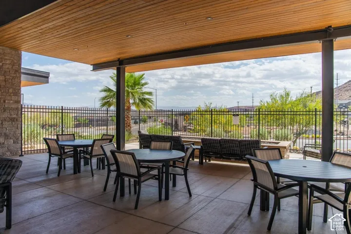 Covered patio with a wood-finish ceiling, stone columns, concrete flooring, and a built-in fire pit