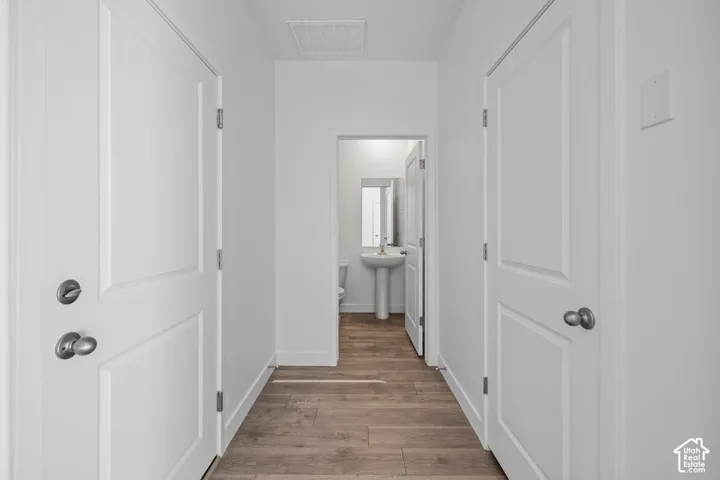 White interior doors with brushed nickel hardware, wood-finish flooring, and a pedestal sink with a mirror