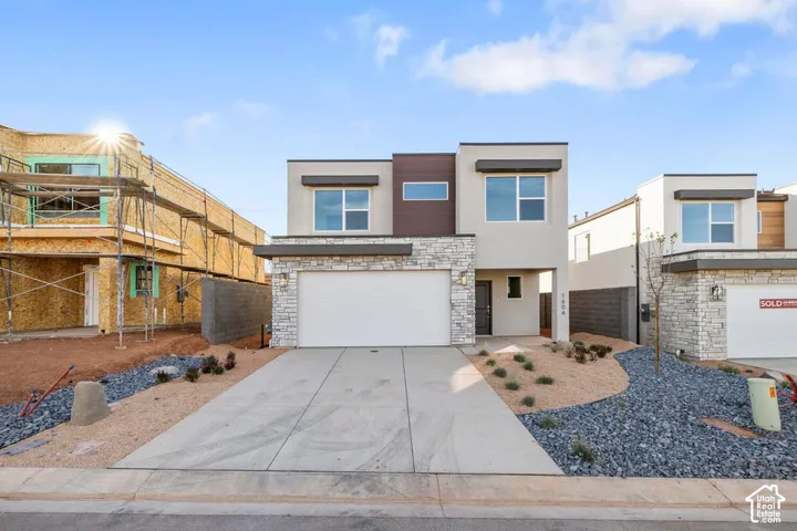 Modern facade with stone veneer accents, integrated garage, and a contemporary entry door