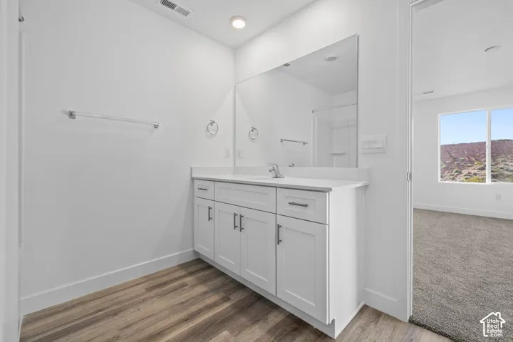 Vanity with white shaker cabinetry, an integrated sink, and a large wall-mounted mirror
