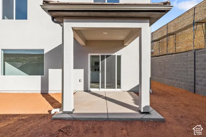 Covered patio with a concrete slab, stucco exterior, and sliding glass door