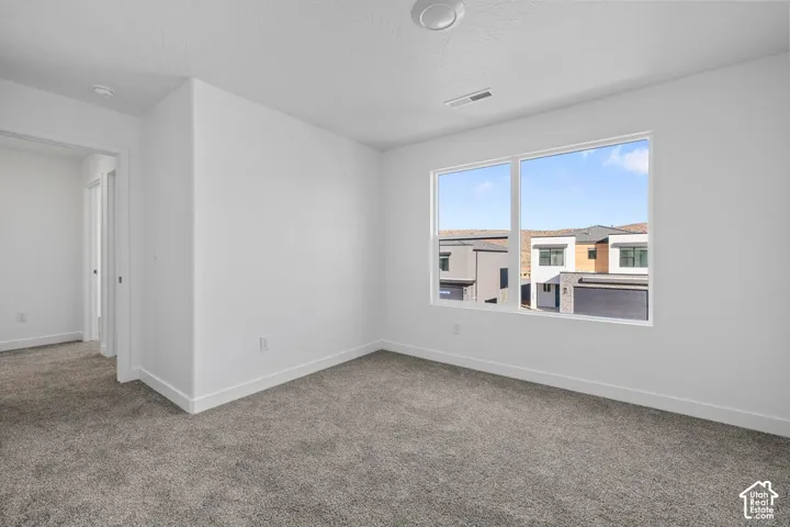 Neutral white walls, plush grey carpeting, and a large window with white trim