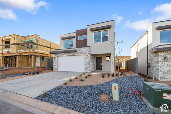 Modern facade featuring a stucco exterior with stone accents, a concrete driveway, and an integrated garage
