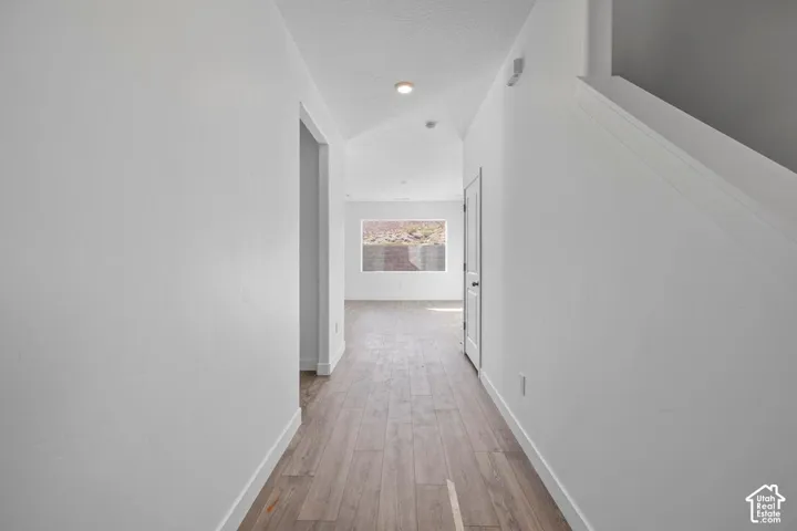 Recessed lighting, wood-finish flooring, white walls, and a window providing natural illumination