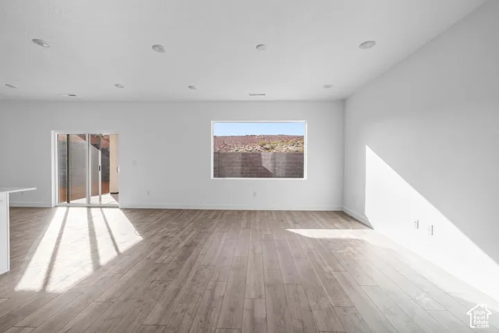 Wood-finish flooring, recessed ceiling lighting, a window with distant scenery, and a sliding glass door