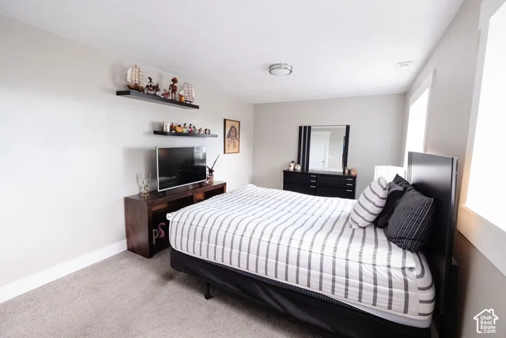 Recessed lighting, wood-finish media console, built-in wall shelving, light gray wall paint, and gray carpet flooring