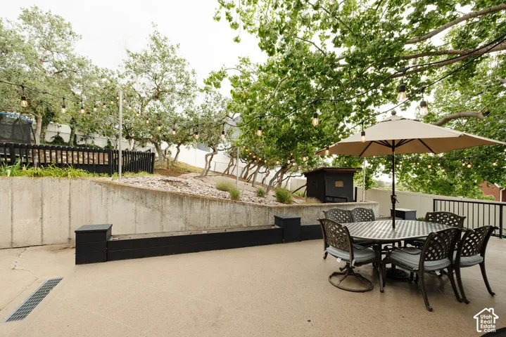 Expansive concrete patio with integrated drainage, concrete retaining wall, and black planter box