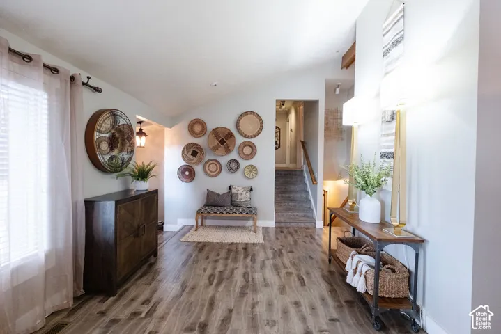 Vaulted ceiling, wood-finish flooring, staircase with carpeted treads, recessed lighting, and wall sconce