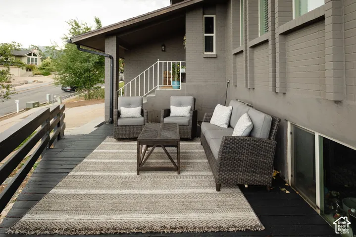 Expansive outdoor deck with dark wood-finish planking, featuring a painted brick exterior and white railing
