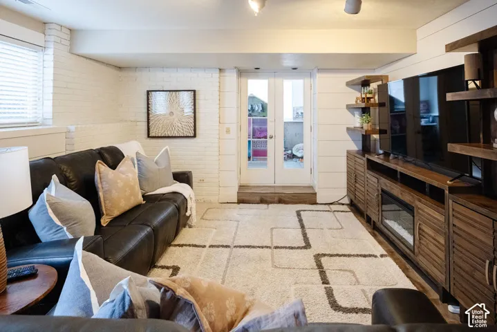 White painted brick walls with shiplap accent, built-in entertainment center with shelves, and double glass-paneled doors