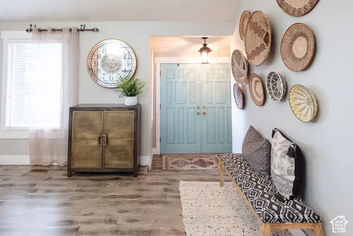 Wood-finish flooring, light blue interior double doors, and a window with white blinds