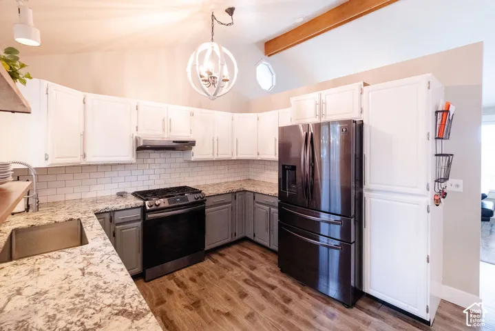 Kitchen featuring wood-finish flooring, white cabinetry, subway tile backsplash, and a vaulted ceiling with exposed beam