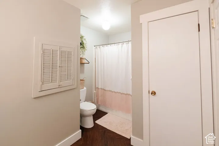 Wood-finish flooring with white trim, a built-in shutter feature, and a white interior door with a brass-finish doorknob