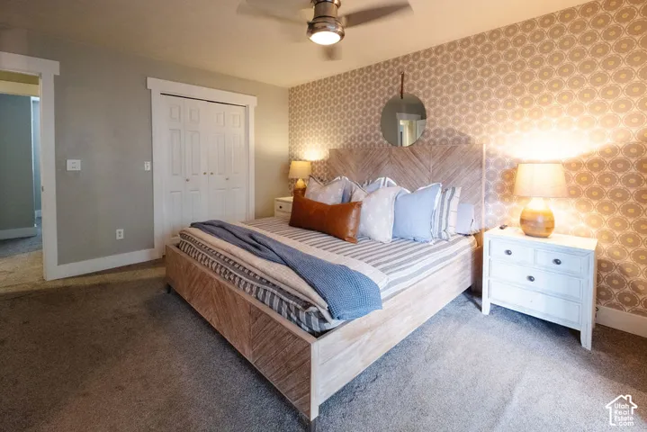 Wall-to-wall carpeting, wood-finish bed frame, and patterned accent wall