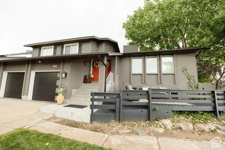 Contemporary split-level exterior with a two-car garage, concrete driveway, and a wood-slat deck