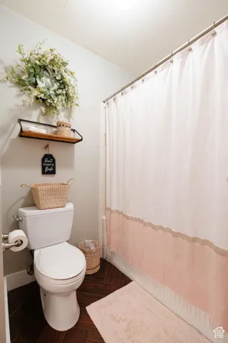White toilet with dark wood-finish flooring