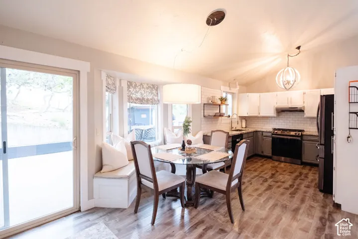 Wood-finish flooring, vaulted ceiling, white subway tile backsplash, built-in window seating, and a sliding glass door