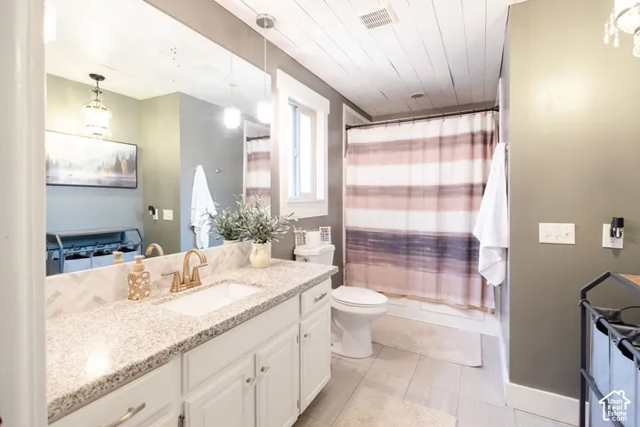 White vanity with light-colored countertop, undermount sink, and brass-finish faucet
