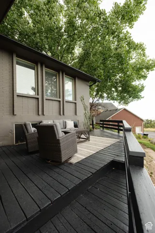 Expansive multi-level wood deck, gray brick exterior, multiple windows with blinds, and durable dark-painted deck surface