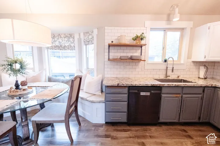 Kitchen with wood-finish flooring, subway tile backsplash, and granite countertops