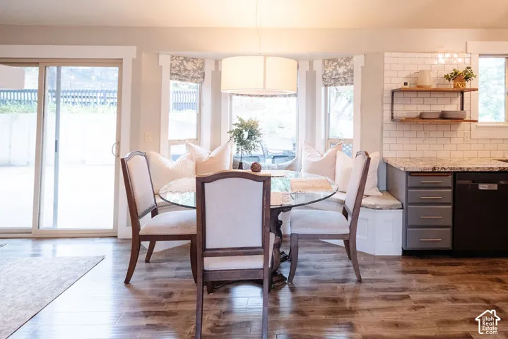 Wood-finish flooring, sliding glass patio door, built-in bay window seating, white subway tile backsplash, and open wood shelving