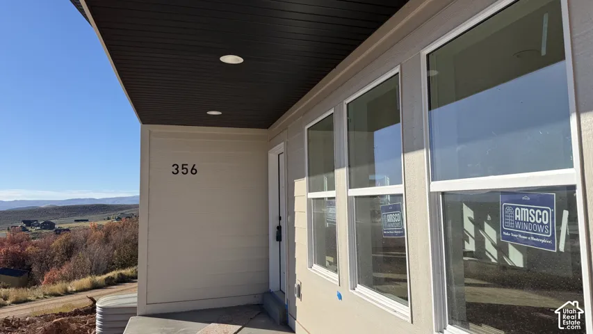 Recessed lighting in a dark soffit, light-colored siding, and multiple windows with white frames
