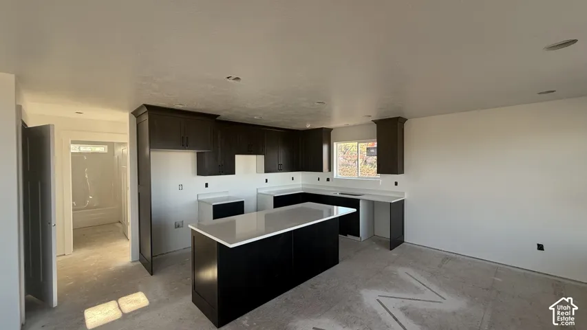 Kitchen featuring dark wood cabinetry, white countertops, a center island, and recessed lighting