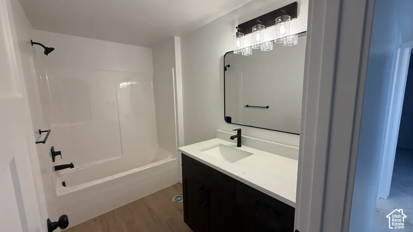Modern bathroom featuring a dark wood-finish vanity with a white countertop, a rectangular undermount sink, and matte black fixtures