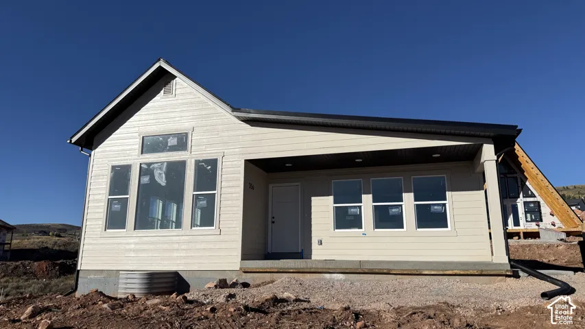 Newly constructed home with light-colored siding, multiple windows, and a covered entry