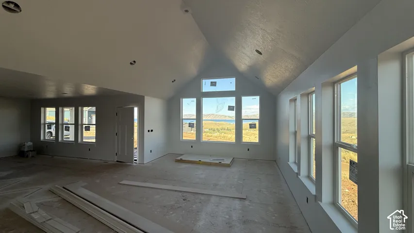 Vaulted ceiling, recessed lighting, numerous windows, white trim, and white walls