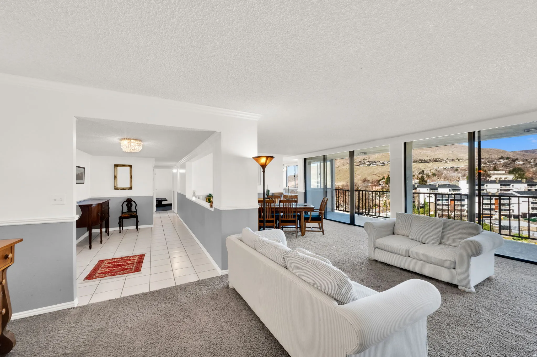 Expansive living area with full-height windows, a glass balcony, and mountain scenery