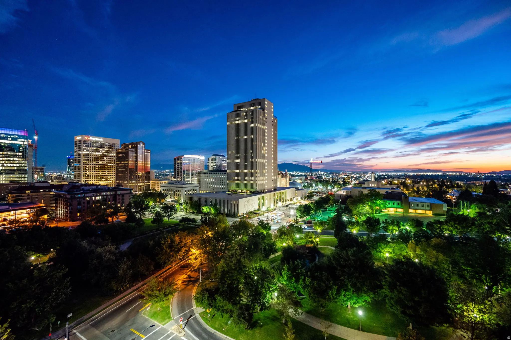 Urban skyline with illuminated high-rise buildings and surrounding green spaces