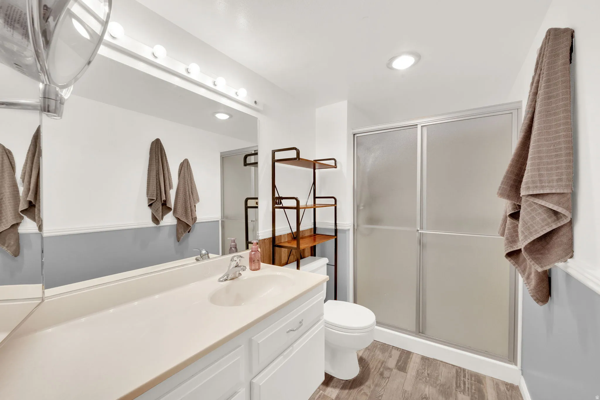 Bathroom featuring a vanity with integrated sink, full-width mirror, and a shower with sliding opaque glass doors
