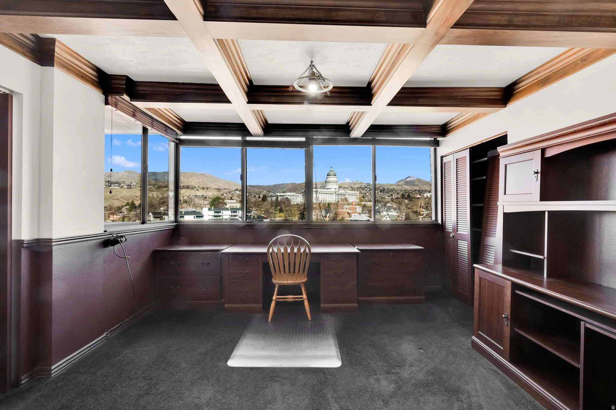 Built-in desk, built-in storage cabinetry, coffered ceiling, carpet flooring, and expansive exterior scenery