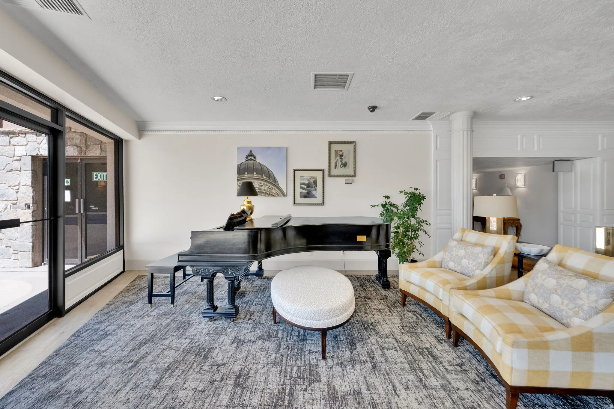 Expansive windows with black framing, wood-finish flooring, a decorative grand piano, and detailed architectural wall paneling