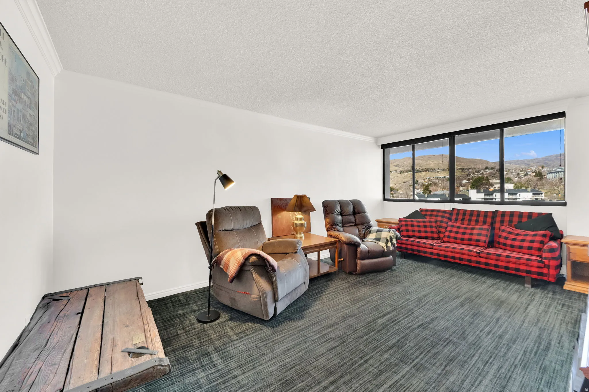 Expansive windows offering mountain scenery, crown molding, and textured ceiling