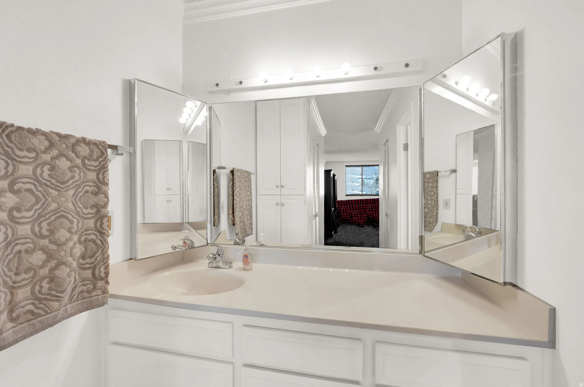 Vanity with integrated sink, tri-fold mirror, and built-in upper and lower cabinetry
