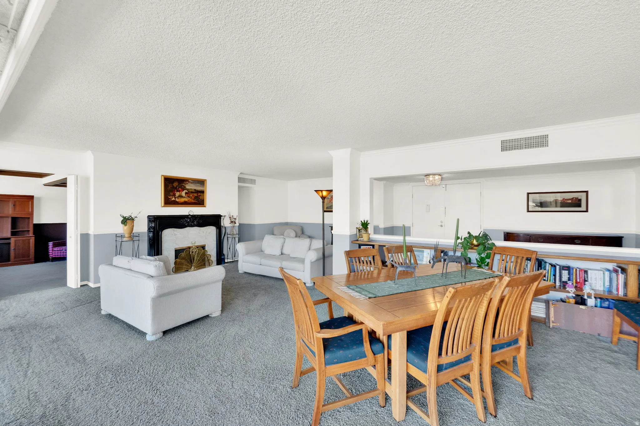 Spacious interior featuring a decorative fireplace with a dark mantel, light-toned carpeting, and a built-in bookshelf