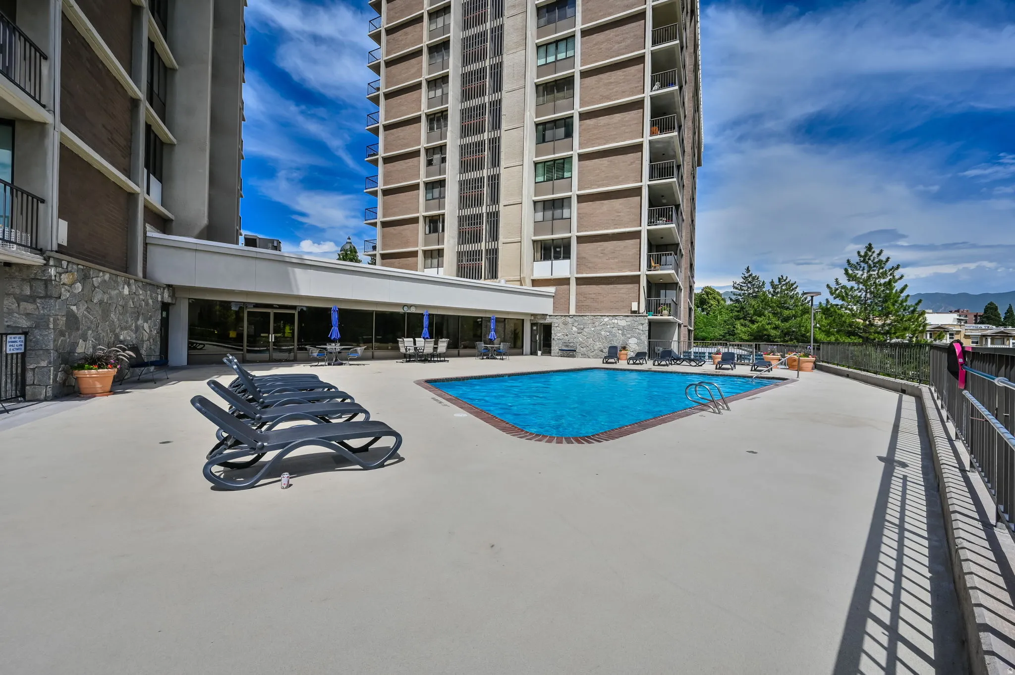 Outdoor swimming pool with a concrete deck, surrounded by lounge seating and dining areas