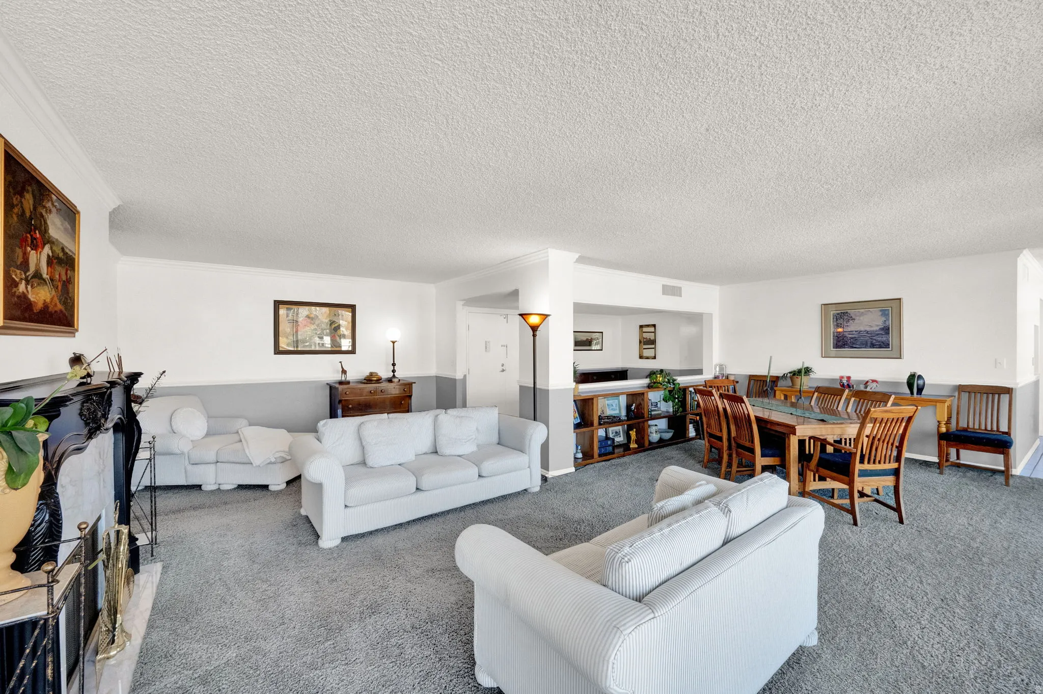 Expansive carpeted living area with a fireplace featuring a black mantel