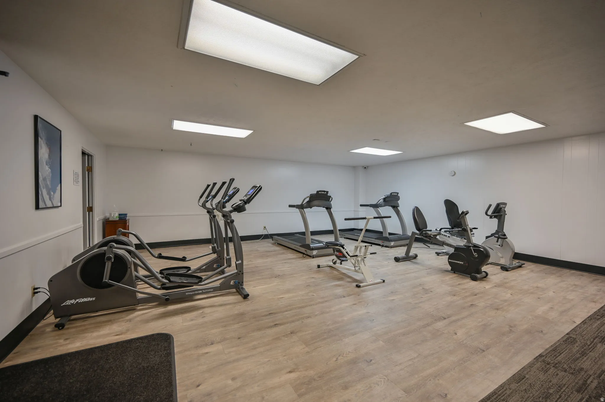 Fitness room featuring wood-finish flooring and recessed ceiling lighting