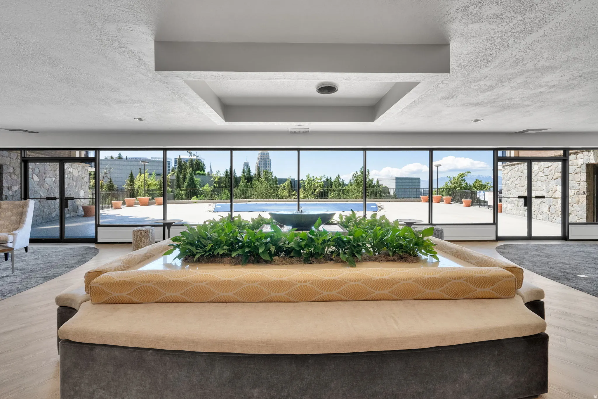 Expansive floor-to-ceiling windows, stone wall accents, recessed lighting, and wood-finish flooring