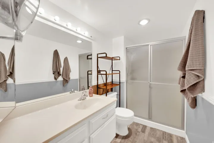 Bathroom featuring a vanity with integrated sink, full-width mirror, and a shower with sliding opaque glass doors