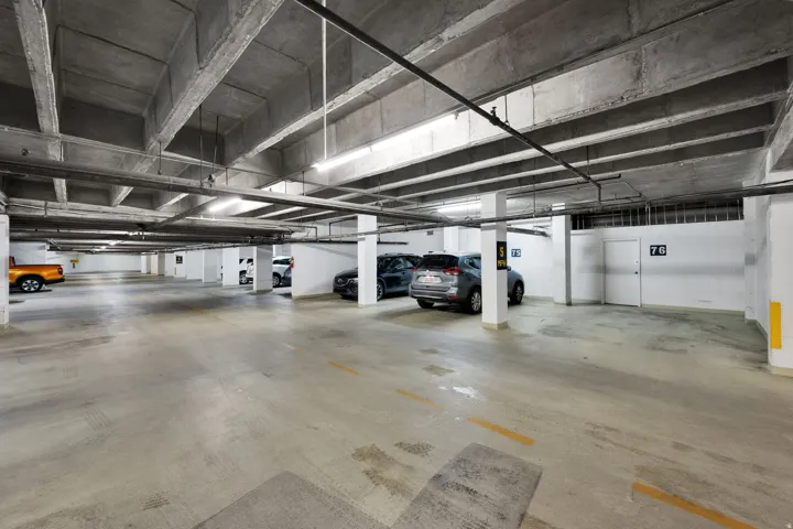 Underground parking garage featuring concrete flooring and exposed concrete ceiling beams