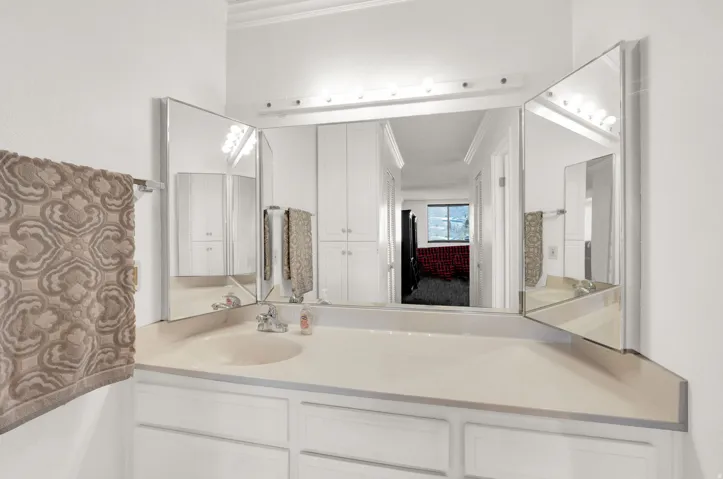 Vanity with integrated sink, tri-fold mirror, and built-in upper and lower cabinetry