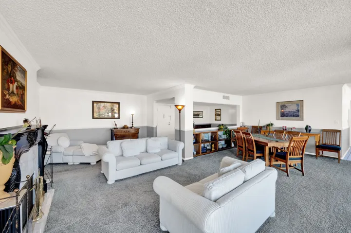 Expansive carpeted living area with a fireplace featuring a black mantel