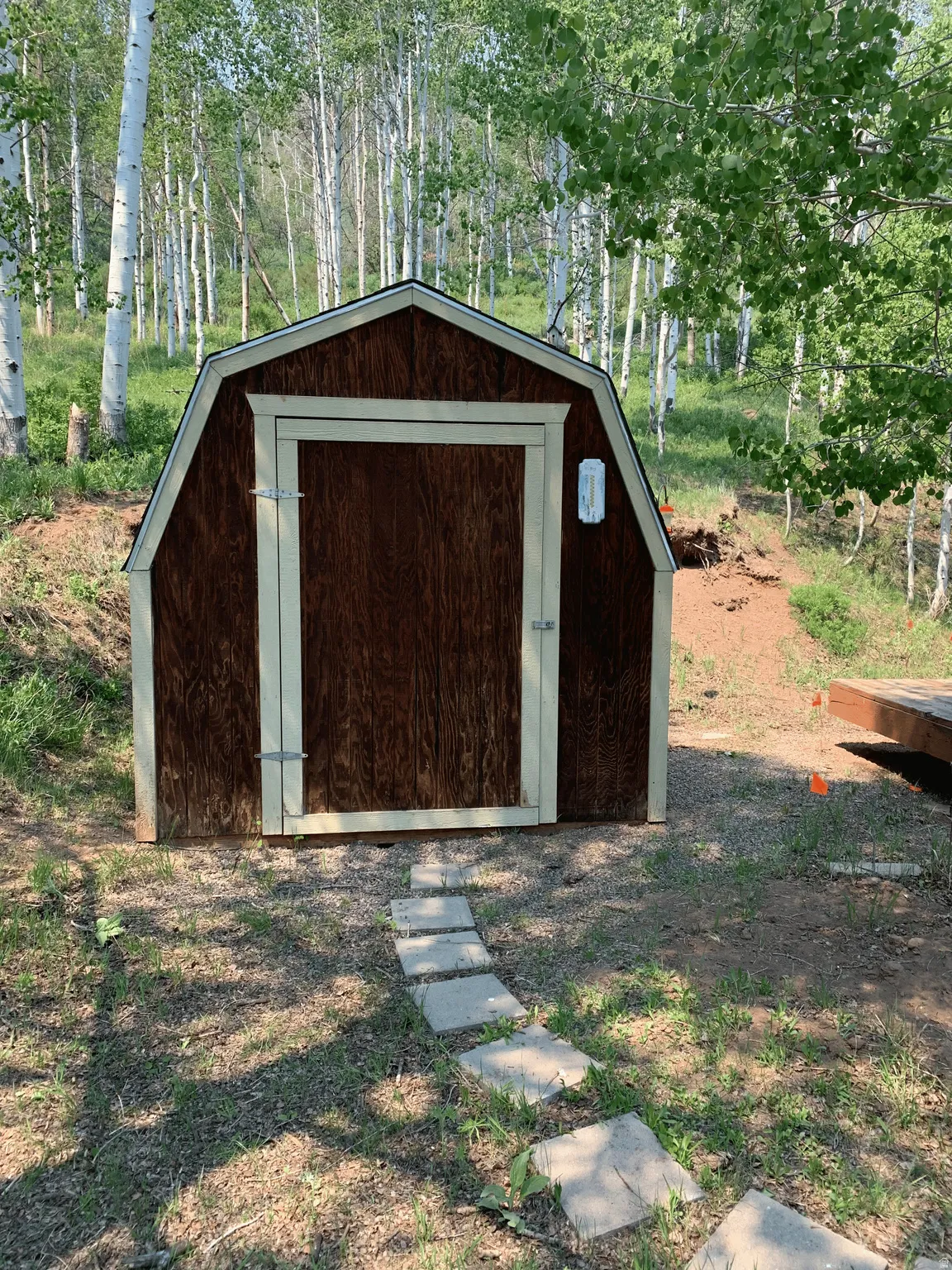 Wood-sided shed with a gambrel roof and light-colored trim