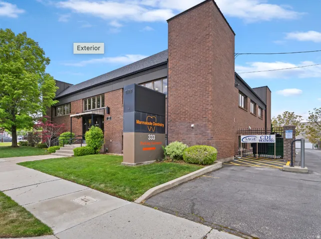 Brick exterior with multiple windows, a prominent building sign, and a paved parking area