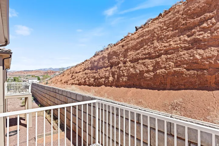 Terraced outdoor space featuring a white railing, a block retaining wall, and a natural rock formation